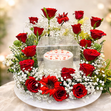 mini vanilla cake surrounded by circular arrangement of 20 red roses, baby breath and red gerberas on white plate, romantic floral cake gift by Send My Feelings