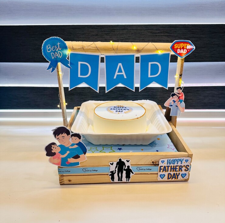 Super Dad Bento Celebration featuring a 350 g bento cake in a wooden display tray with fairy lights, DAD banner, Super Dad cutouts and Fathers Day decorations by Send My Feelings.