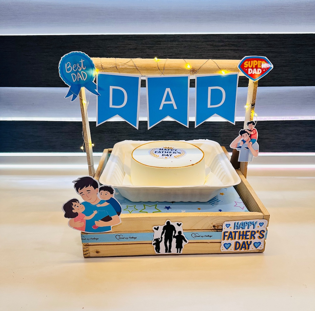 Super Dad Bento Celebration featuring a 350 g bento cake in a wooden display tray with fairy lights, DAD banner, Super Dad cutouts and Fathers Day decorations by Send My Feelings.