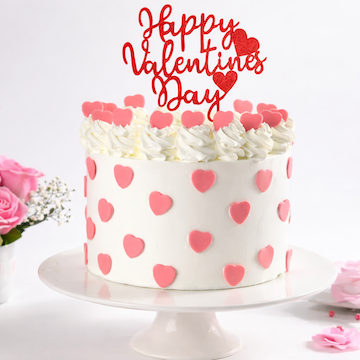 Red velvet Valentine cake with heart decorations and Happy Valentine’s Day topper on white cream frosting